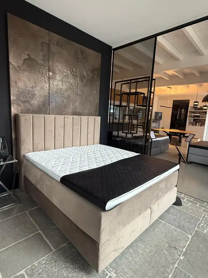 Beiges Boxspringbett mit gepolstertem Kopfteil im Showroom